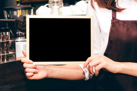 Barista holding chalkboard  in coffee shop restaurantの写真素材