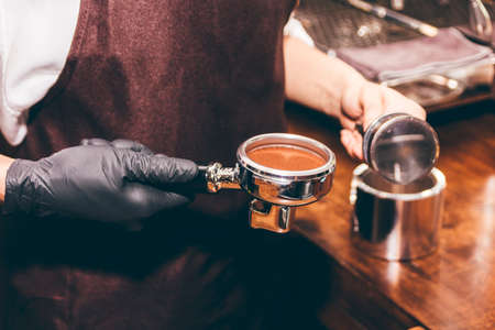 Barista using tamper to makes coffees in coffee bar