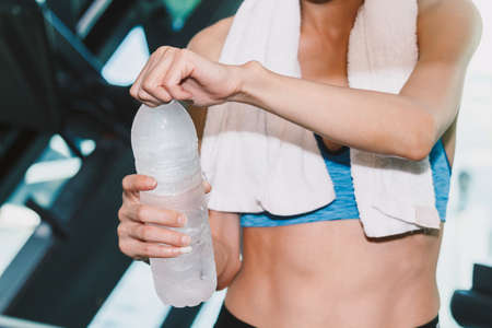 Sporty woman holdind water bottle with towel at the gym.fitness and lifestyle conceptの写真素材