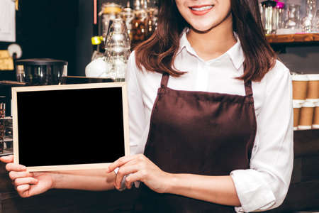 Barista holding chalkboard  in coffee shop restaurantの写真素材