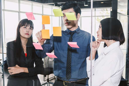 Businessman point with sticky notes on glass windowの写真素材