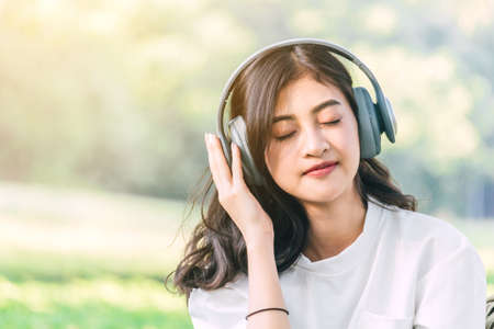 Woman relax with headphones listening to music sitting on grass in parkの写真素材