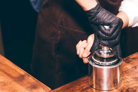 Barista using tamper to makes coffees in coffee barの写真素材