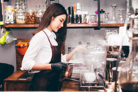 Women Barista using coffee machine for making coffee in the cafeの写真素材