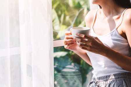 Woman drinking coffee in bedroom in the morningの写真素材