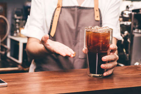 Woman barista giving coffee to customer at cafeの写真素材