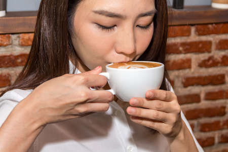 Woman drinking coffee at coffee shopの写真素材