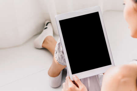 Woman using digital tablet computer in bedroom