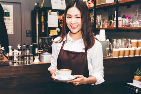 Barista holding coffee in coffee shopの写真素材