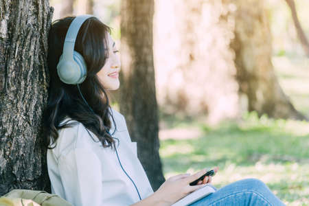 Woman relax with headphones listening to music sitting on grass in parkの写真素材