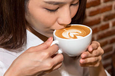 Woman drinking coffee at coffee shopの写真素材