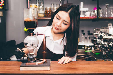 Women Barista making coffee on syphon coffee maker in the cafeの写真素材