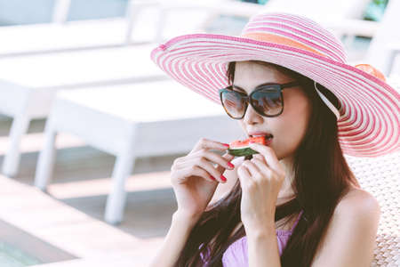 Woman sitting in swimming pool on summer vacation relaxing at resort spaの写真素材