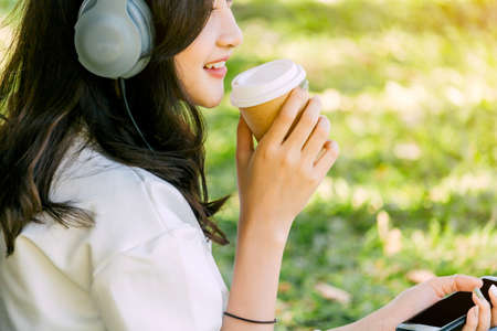 Woman relax with headphones listening to music sitting on grass in parkの写真素材