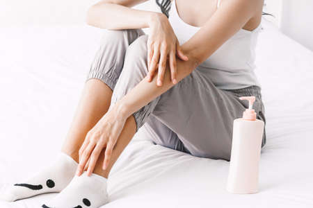 Woman applying cream on hand on bedの写真素材