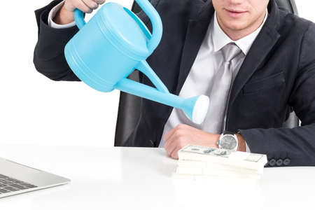 Businessman with watering can on money dollars isolated on white backgroundの写真素材