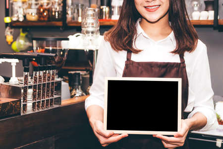 Barista holding chalkboard  in coffee shop restaurantの写真素材