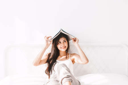 Woman with book on bed in the morning