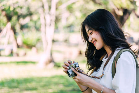 Asian woman taking picture with camera in park