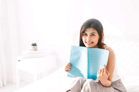 Woman reading book on bed in the morning