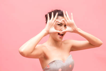 Portrait of fashion smilling young beautiful woman model posing on pink backgroundの写真素材
