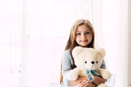 Cute little girl kid hugging teddy bears on the bed at homeの写真素材