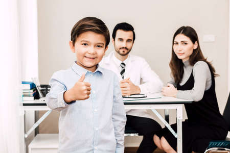 Doctor with mother and her little boy looking at camera and smiling in hospital.healthcare and medicineの写真素材
