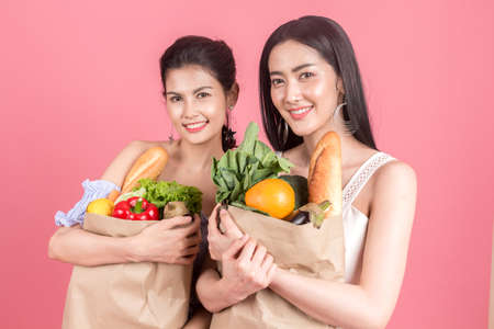 Woman holding shopping paper bag with fruit and vegetables diet healthy eating on pink backgroundの写真素材