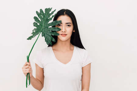 Portrait of beautiful woman behind green leaf.skin care and organic cosmetics concept