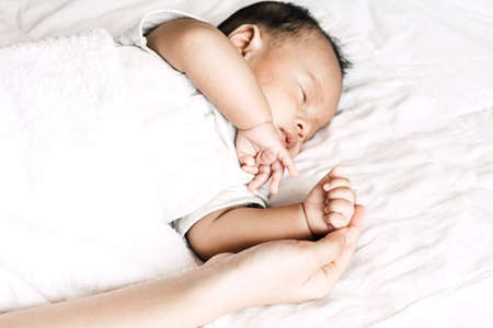 Sleeping baby hand in hand mother.Love of family conceptの写真素材