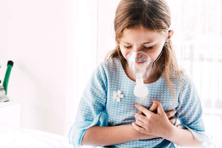 Cute little girl with nebulizer mask in the hospitalの写真素材