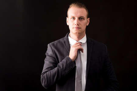 Handsome Businessman with black suit isolated on black backgroundの写真素材