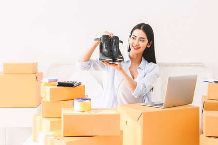 Young woman freelancer working sme business online shopping and packing shoes with cardboard box on bed at home - Business online shipping and delivery conceptの写真素材