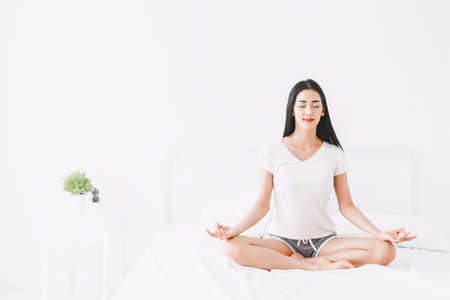 Woman practicing yoga at home in bedroomの写真素材