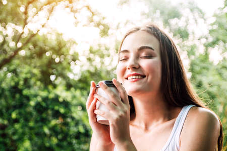 Young woman relax and enjoying drinking coffee on natural morning fresh air backgroundの写真素材