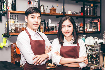 Portrait of couple barista working and standing behind the counter bar in a cafeの写真素材