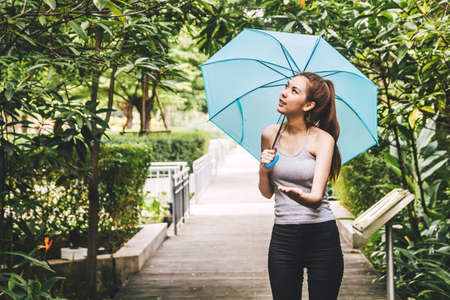 Woman holding umbrella and enjoy to spring rain at green parkの写真素材