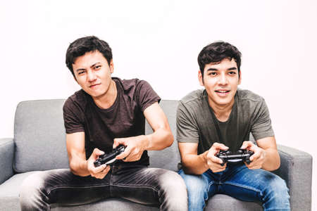 Two friends sitting on sofa and enjoying play video game together at home