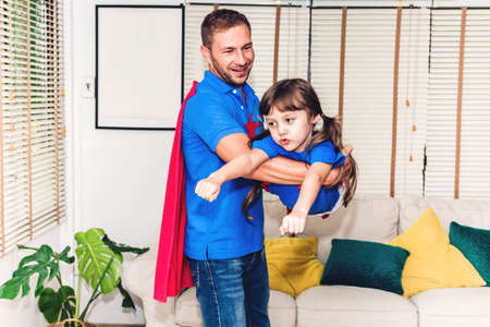 Father with little daughter in superhero costume having fun and playing superheroes together at home.Love of family and father day conceptの写真素材