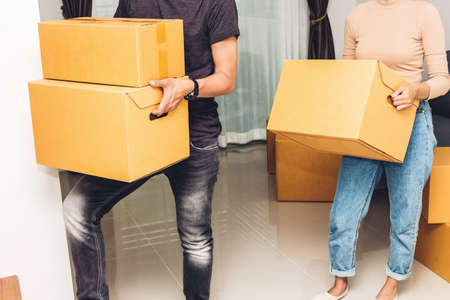 Happy young couple carrying boxes and moving into their new home.House moving and real estate...