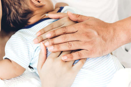 Mother and father holding baby in her arms in a white bedroom.Love of family conceptの写真素材