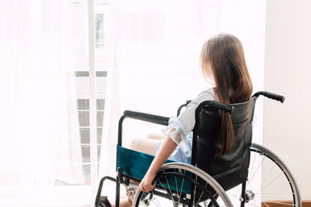 Little girl sitting on wheelchair in the hospitalの写真素材
