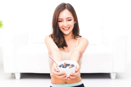 Woman holding yogurt and mixed berries blueberries with strawberries while relaxing at home.dieting concept.healthy lifestyleの写真素材