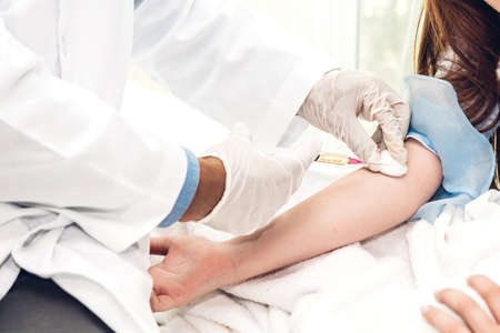 Doctor in protective gloves giving injection with little girl child on doctors table in hospital.healthcare and medicineの写真素材