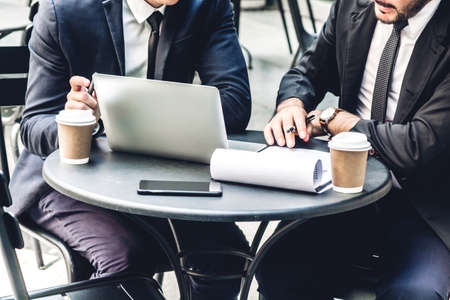 Image of two businessman coworkers in black suit talking and working with laptop computer and...