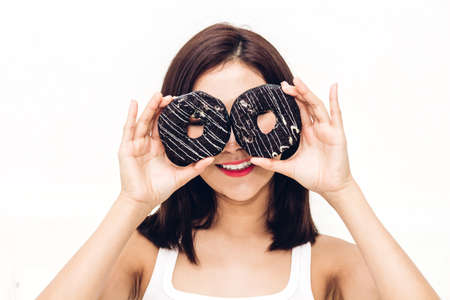 Beautiful woman enjoy eating chocolate donut cake at home.unhealthy and Junk food conceptの写真素材
