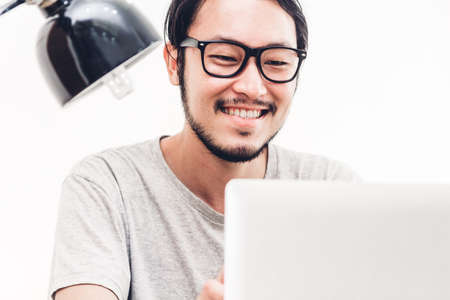 Happy man relaxing and using digital laptop computer on the bed at home.man checking social apps and working.wireless technology conceptの写真素材