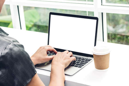 Woman relaxing and using digital laptop computer with blank white screen and coffee cup at...