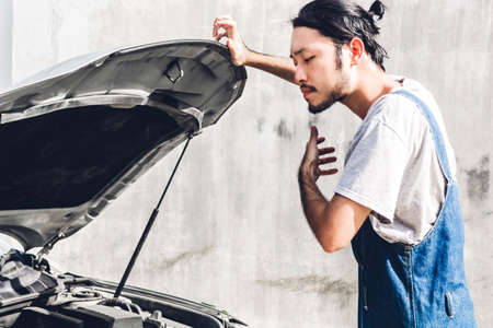 Professional car mechanic in uniform  fixing a car engine and repairing checking under the car hood in auto serviceの写真素材