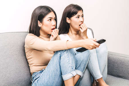Two woman friends  watching television together on sofa at home.Friendship and party concept